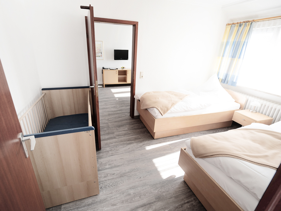 SoVD - helles Familienzimmer mit hölzernem Fußboden, zwei Einzelbetten und einem Babybett