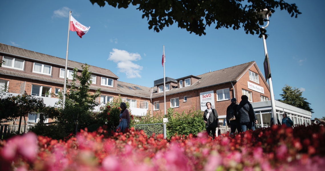 SoVD - laufende Personen vor dem Erholungszentrum Büsum Gebäude aus Froschperspektive