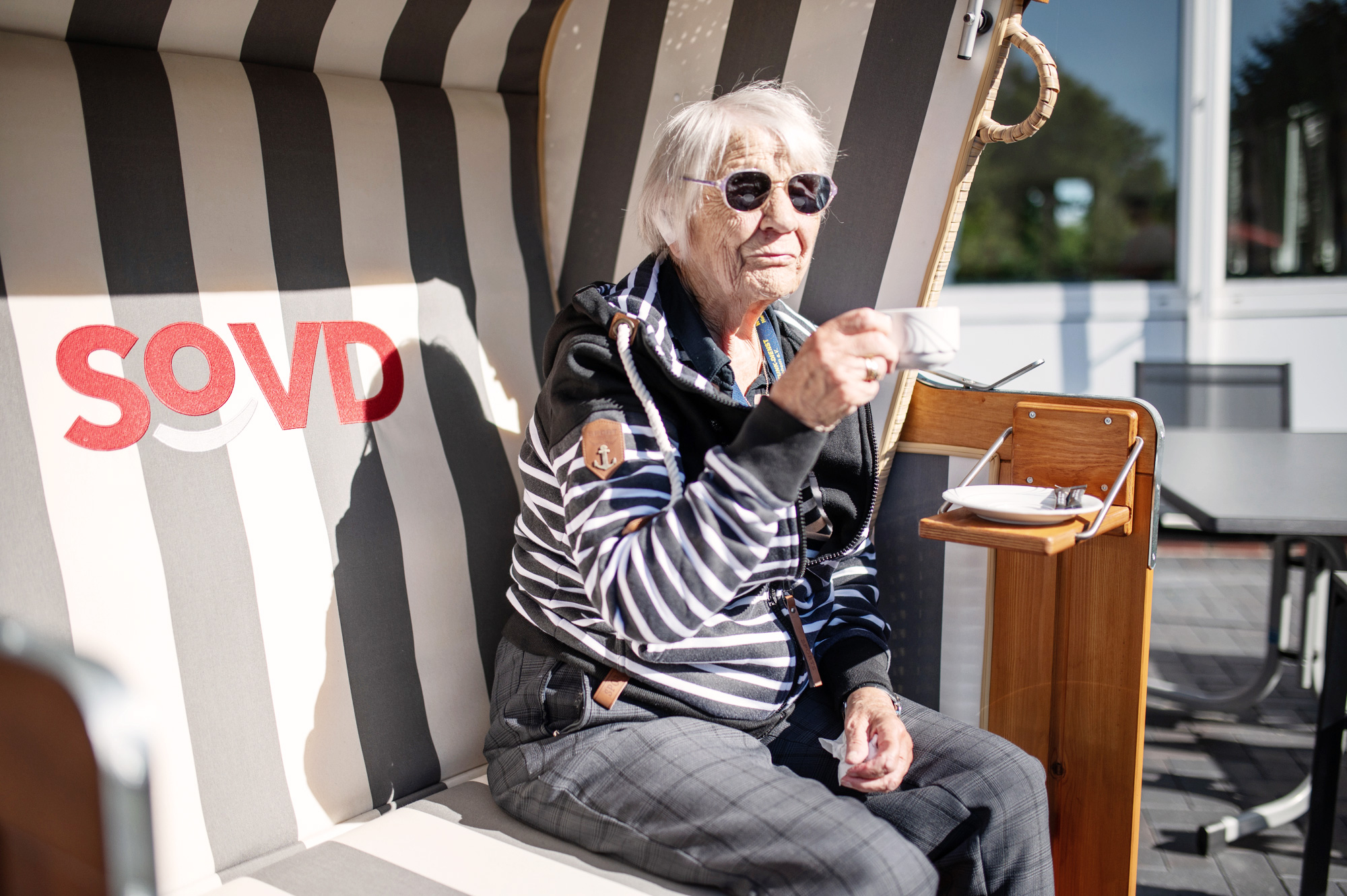 Seniorin im Strandkorb mit Heißgetränk