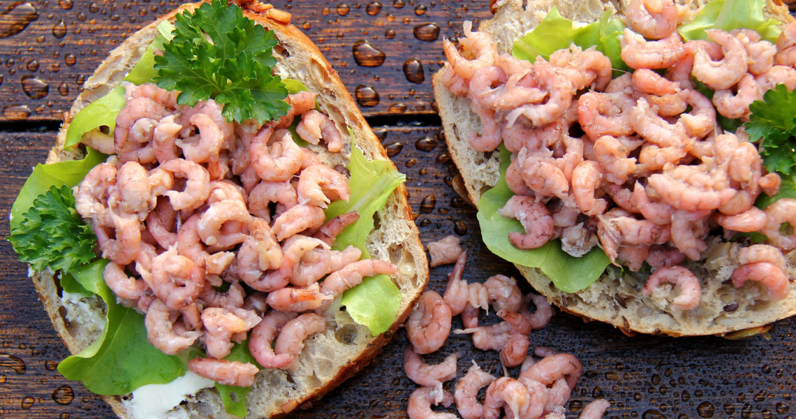 Krabbenbrötchen mit Salat und Petersilie auf nassem Holztisch